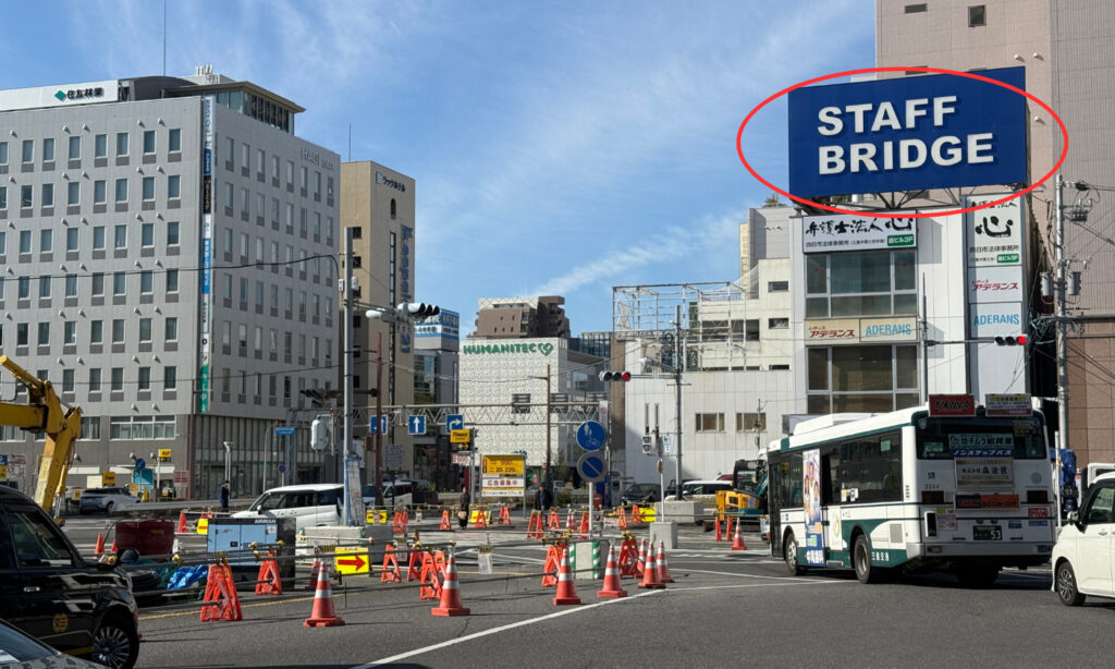 正面に「STAFF BRIDGE」の看板が見える交差点です。そのまま直進方向へ進みます。
