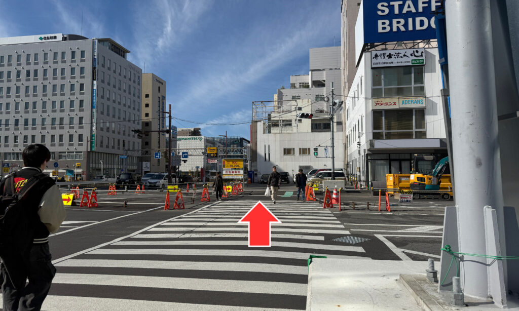 横断歩道をまっすぐ渡ります。 渡った先もそのまま直進。両側にビルが並ぶエリアです。